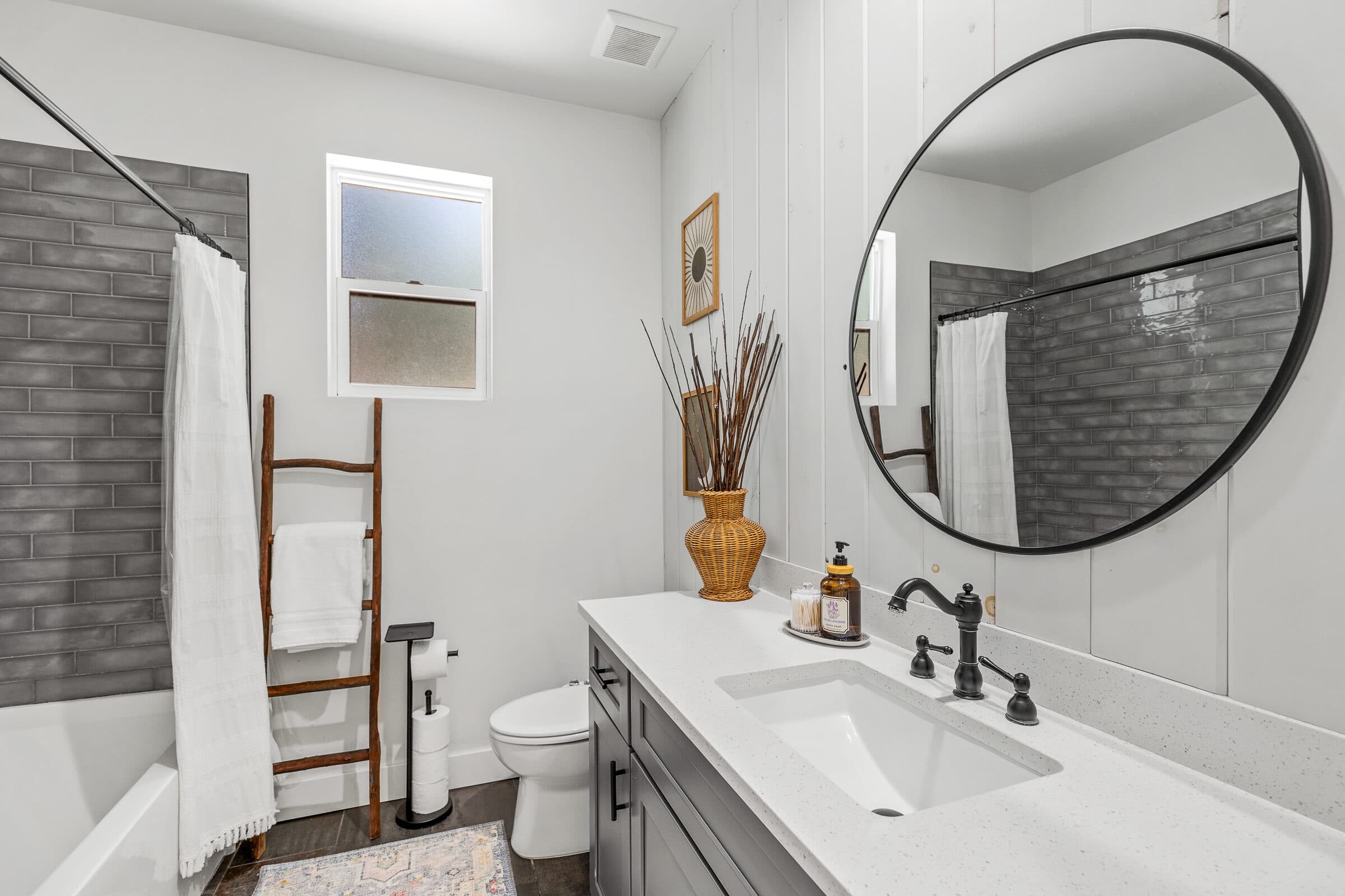 Bathroom vanity with a round mirror and gray cabinetry