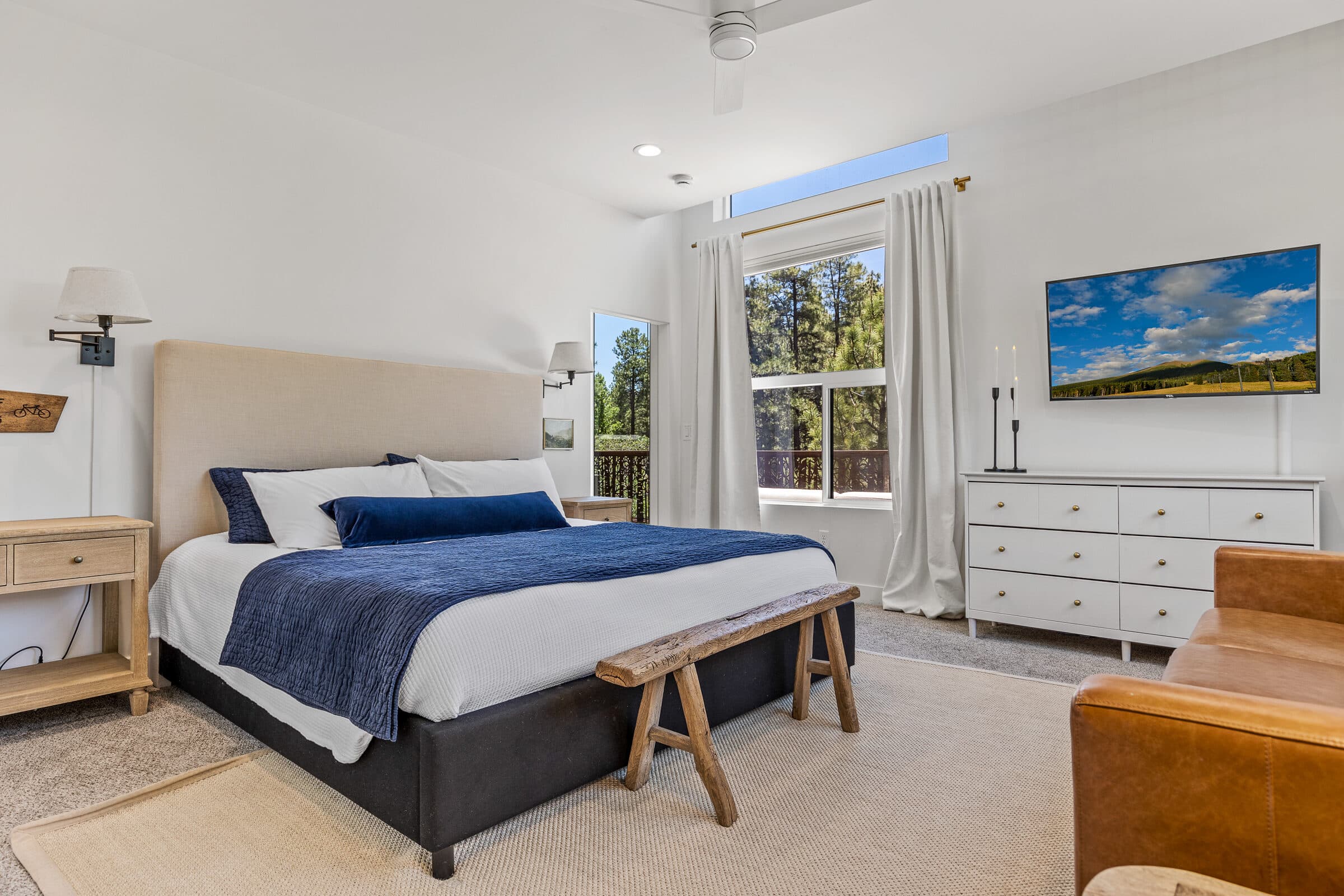Bedroom with crisp navy linens and a forest-view window
