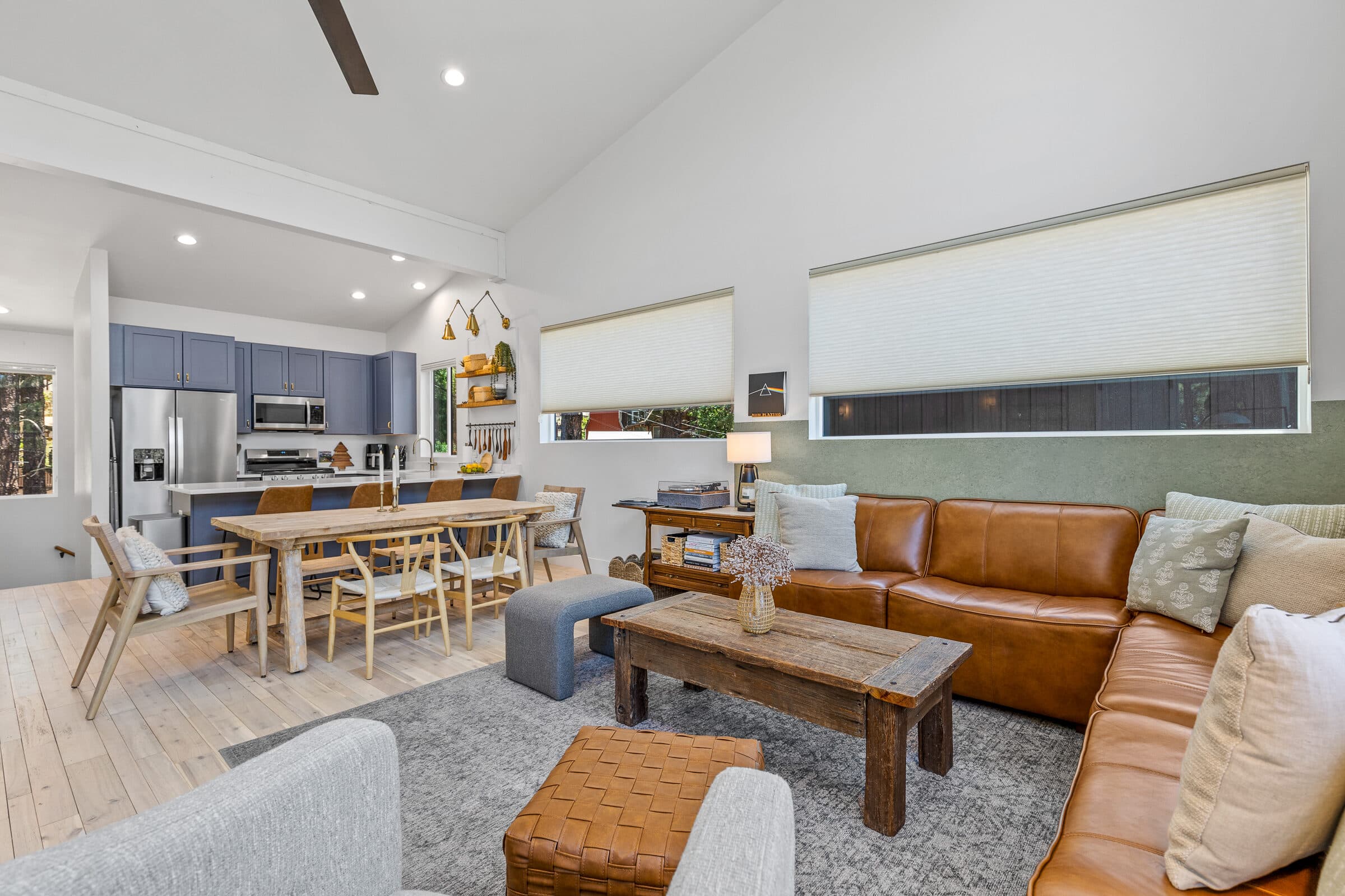 Vaulted great room with a leather sectional and a wall of windows