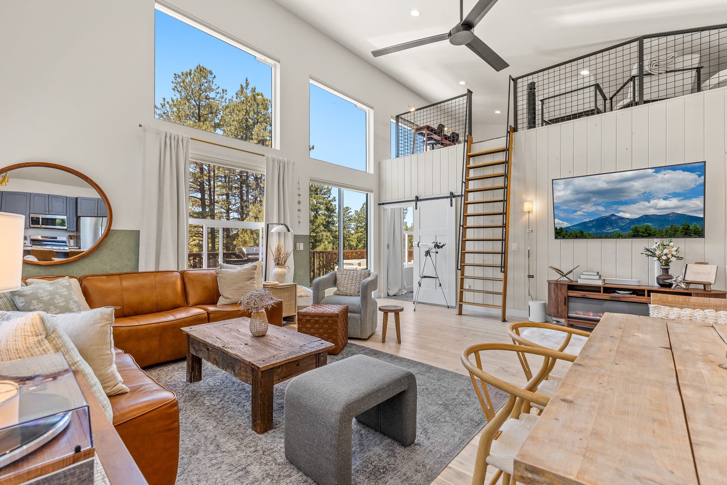 The Starlight Loft's vaulted great room with a wall of windows looking into the Flagstaff pines